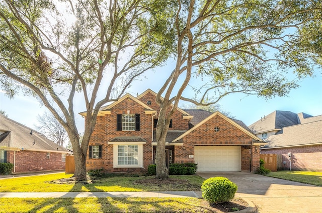 traditional home with a garage, brick siding, driveway, and fence