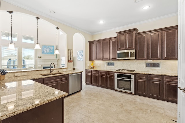 kitchen with dark brown cabinets, appliances with stainless steel finishes, a sink, and pendant lighting