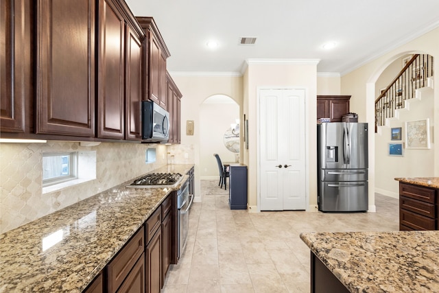 kitchen featuring visible vents, arched walkways, light stone countertops, stainless steel appliances, and crown molding