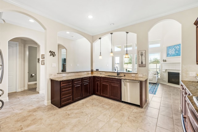 kitchen with dishwasher, light stone counters, decorative light fixtures, a fireplace, and a sink