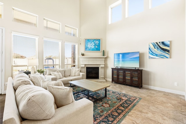 living area with baseboards, a glass covered fireplace, and a healthy amount of sunlight