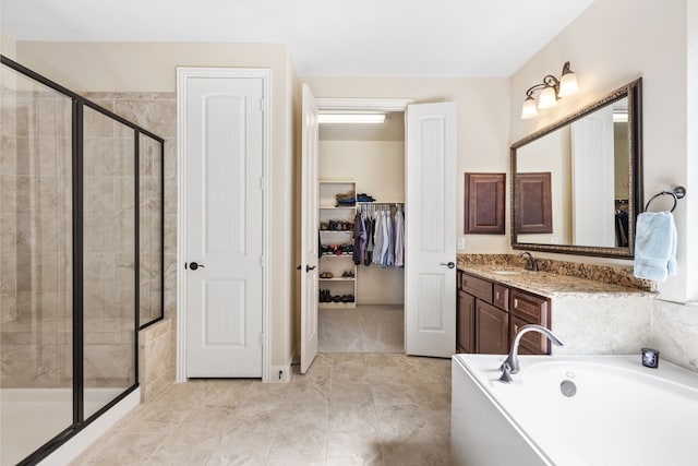 bathroom featuring a bath, a walk in closet, vanity, and a shower stall