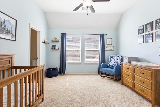 bedroom featuring light colored carpet, vaulted ceiling, a crib, and ceiling fan