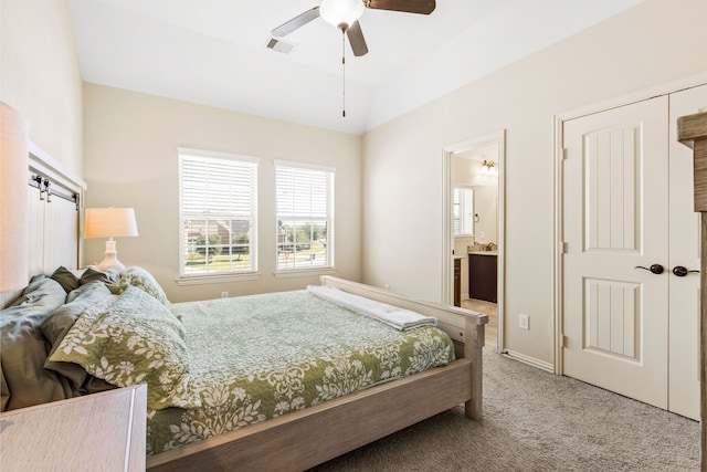 bedroom featuring lofted ceiling, light colored carpet, visible vents, connected bathroom, and ceiling fan