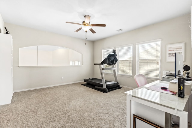 workout area with baseboards, visible vents, a ceiling fan, and light colored carpet