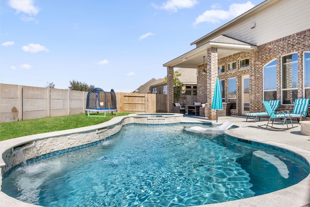 view of pool with a patio area, a fenced backyard, a trampoline, and a pool with connected hot tub