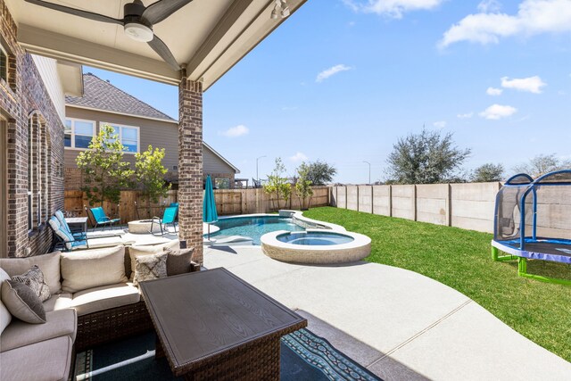 view of patio / terrace with a trampoline, a pool with connected hot tub, a fenced backyard, and outdoor lounge area