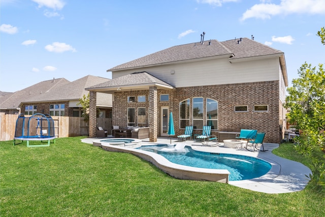 back of property featuring a fire pit, a patio, a trampoline, fence, and brick siding