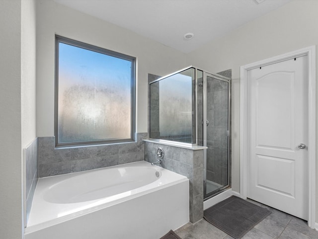 bathroom featuring a stall shower, tile patterned flooring, and a garden tub