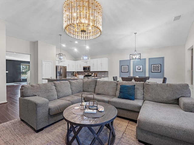 living room featuring visible vents, vaulted ceiling, wood finished floors, and a chandelier