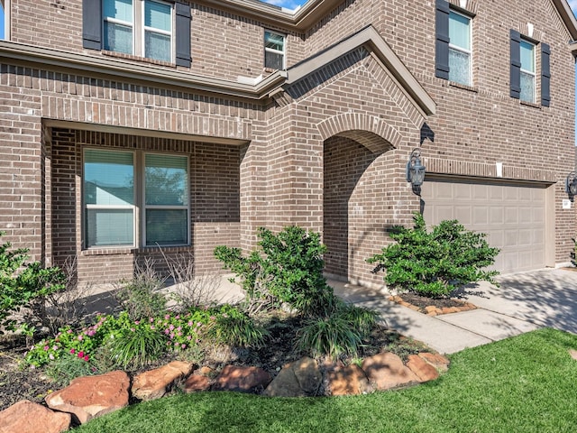 entrance to property featuring a garage and brick siding