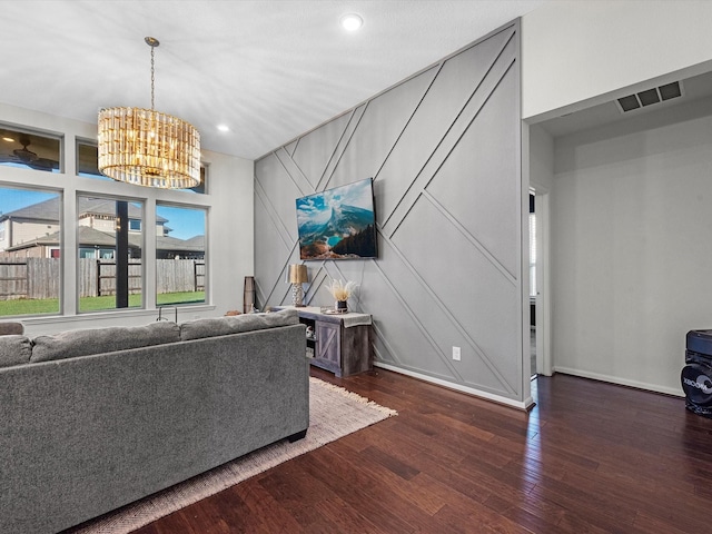 unfurnished living room featuring recessed lighting, dark wood-type flooring, visible vents, baseboards, and an inviting chandelier