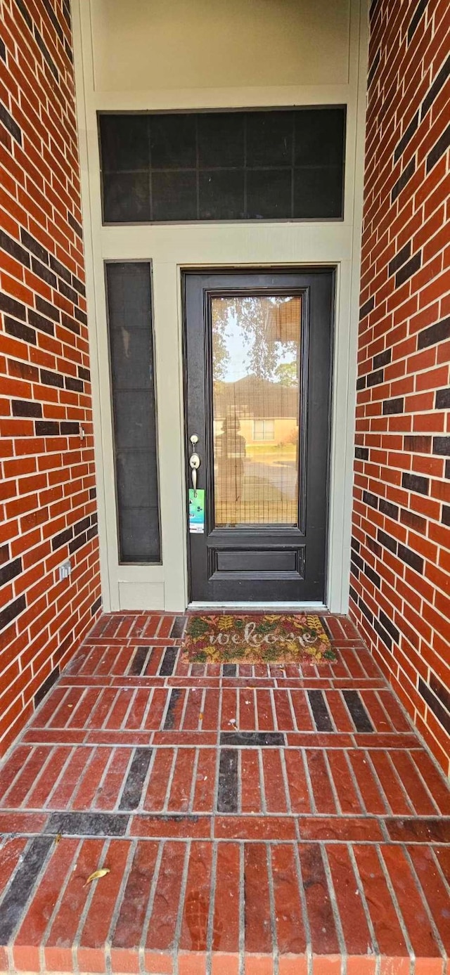 doorway to property with brick siding