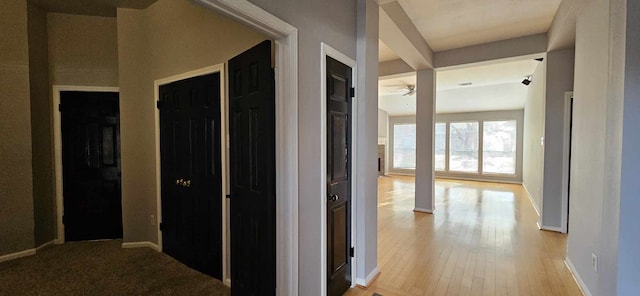 corridor with baseboards and light wood finished floors