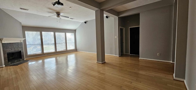 unfurnished living room featuring light wood finished floors, baseboards, a ceiling fan, and a tiled fireplace