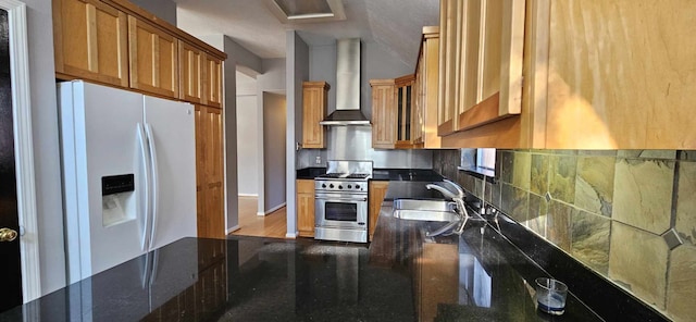 kitchen with a sink, wall chimney range hood, high end stainless steel range, white fridge with ice dispenser, and glass insert cabinets