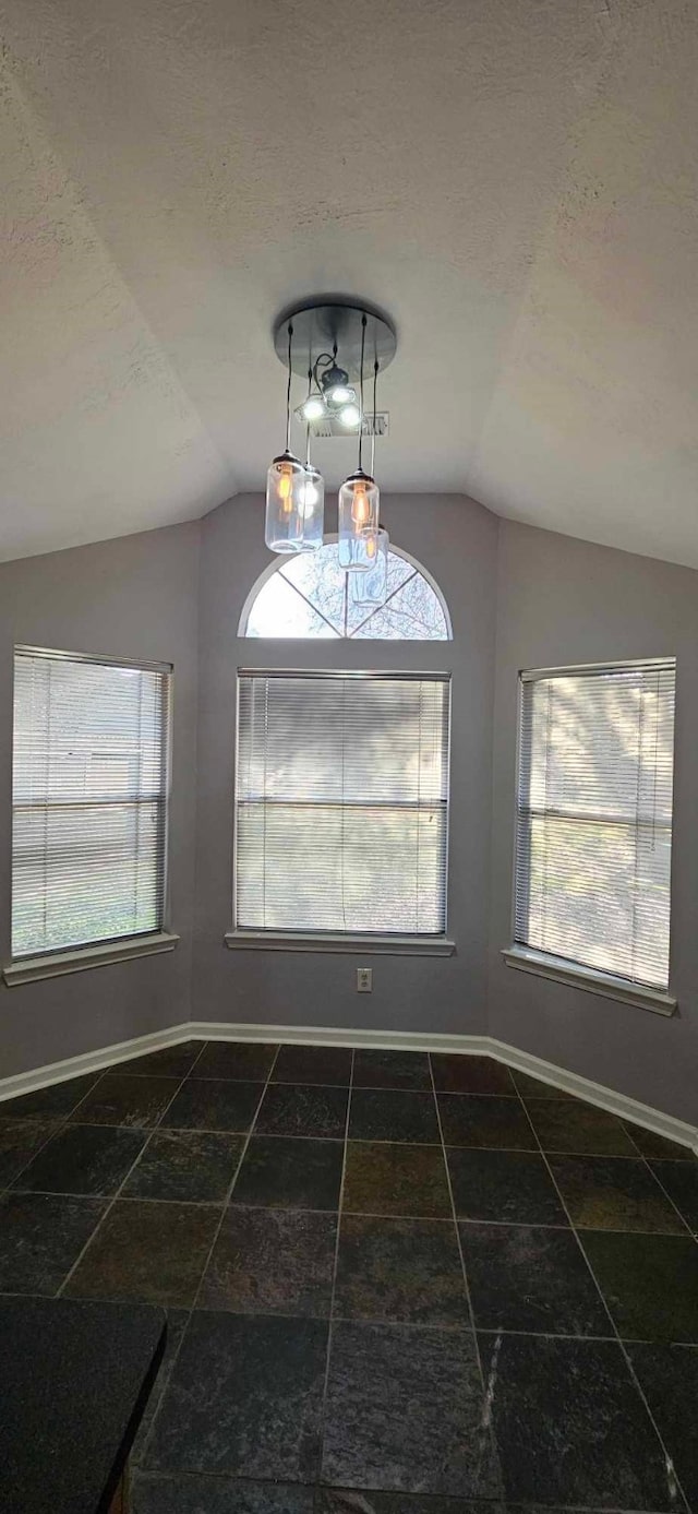 unfurnished dining area with baseboards, vaulted ceiling, and a textured ceiling