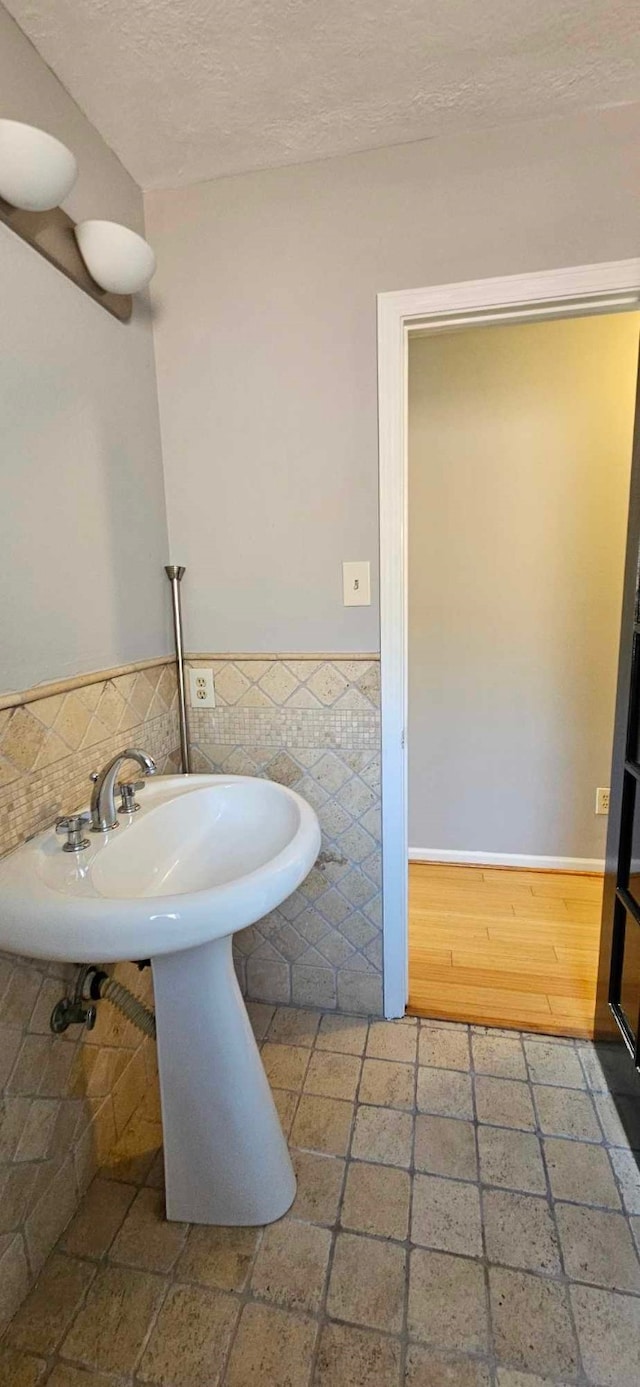 bathroom featuring tile walls, wainscoting, and a textured ceiling