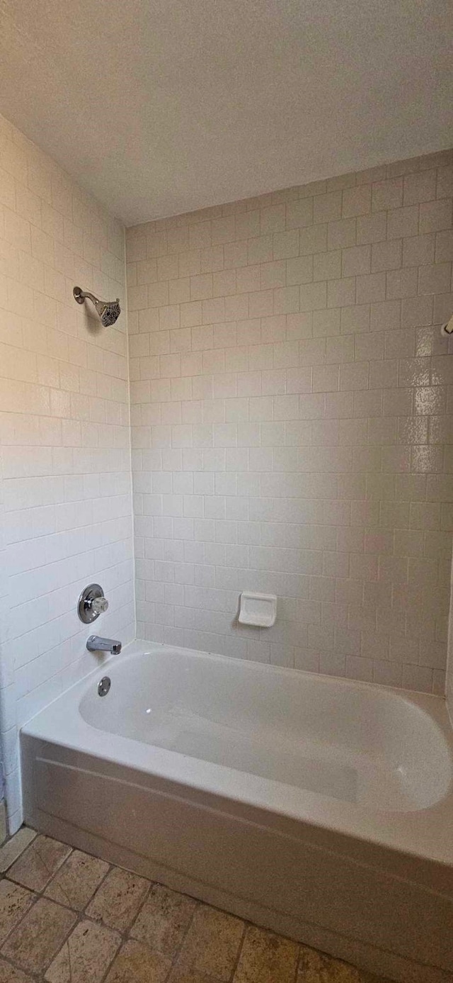 bathroom with a textured ceiling and washtub / shower combination