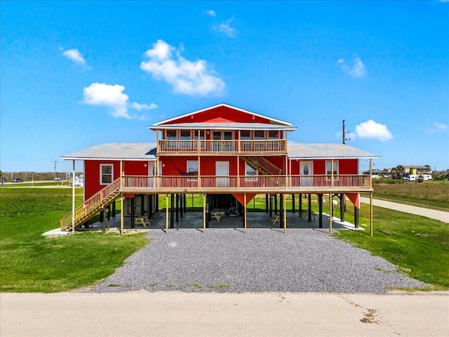 view of front of home with a carport, stairs, a front yard, and gravel driveway