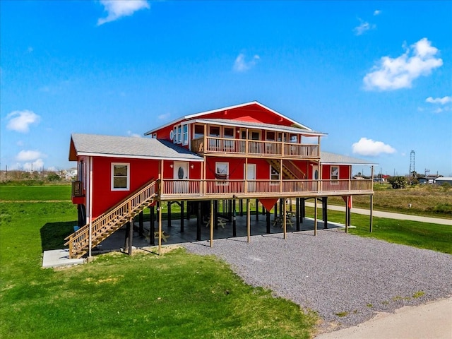 exterior space featuring a yard, gravel driveway, roof with shingles, a carport, and stairs