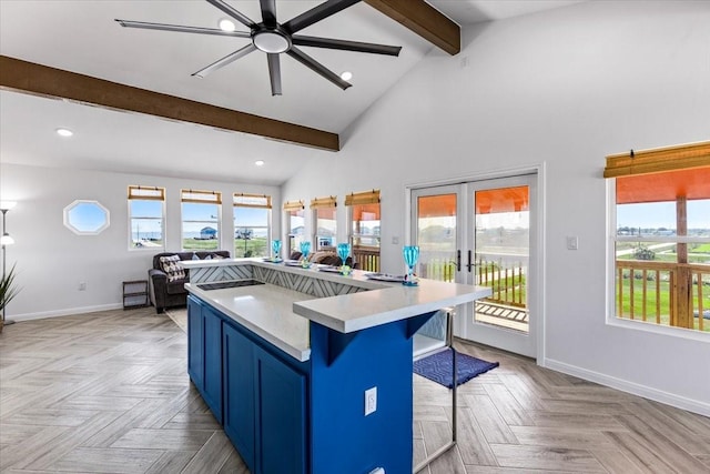 kitchen with a wealth of natural light, beam ceiling, blue cabinetry, open floor plan, and french doors