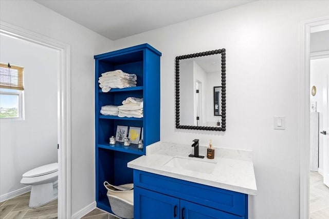 bathroom featuring baseboards, toilet, and vanity