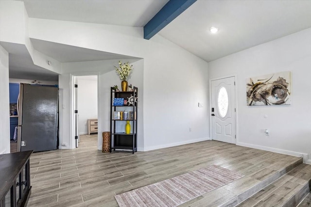 entryway featuring baseboards, light wood-style flooring, and vaulted ceiling with beams