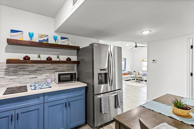 kitchen featuring visible vents, open shelves, stainless steel fridge, blue cabinets, and tasteful backsplash