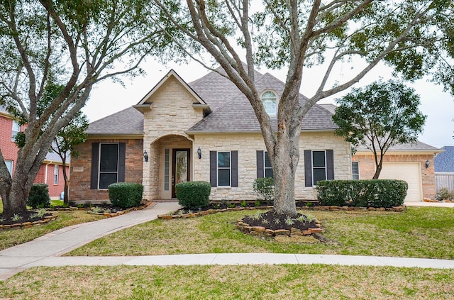 view of front of property featuring a garage, stone siding, a shingled roof, and a front lawn