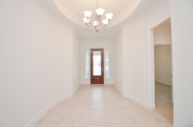 entrance foyer with a chandelier, ornamental molding, a raised ceiling, and baseboards