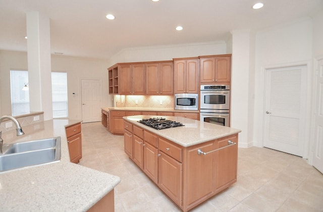 kitchen with light stone counters, stainless steel appliances, decorative backsplash, a sink, and a kitchen island