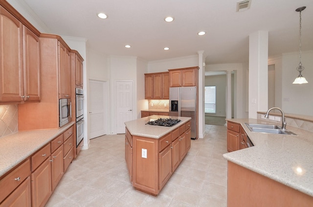 kitchen with visible vents, a kitchen island, appliances with stainless steel finishes, decorative light fixtures, and a sink