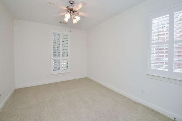 empty room featuring light carpet, visible vents, baseboards, and a ceiling fan