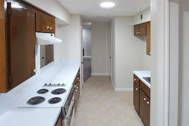 kitchen with cooktop, light countertops, dark brown cabinetry, under cabinet range hood, and baseboards