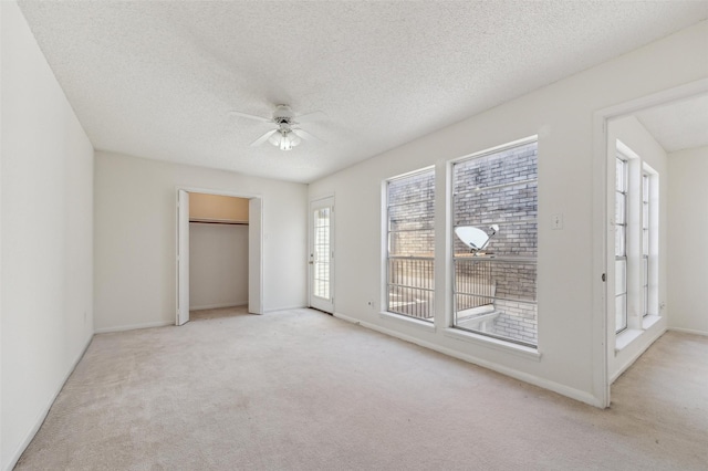 unfurnished bedroom with light carpet, a textured ceiling, and a ceiling fan