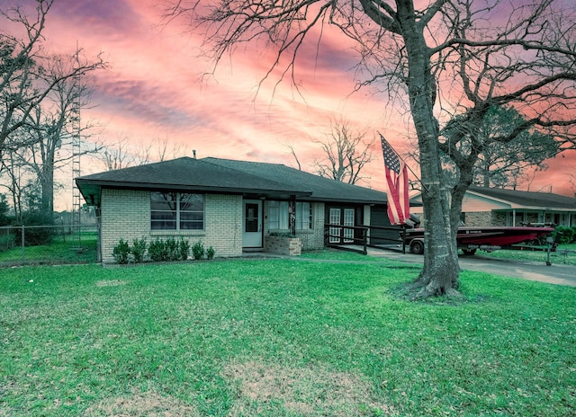 view of front of house featuring a yard, brick siding, and fence