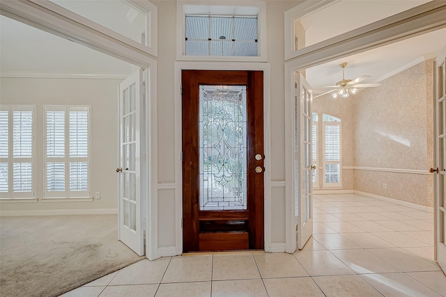 entryway featuring a wealth of natural light, light carpet, crown molding, and wallpapered walls