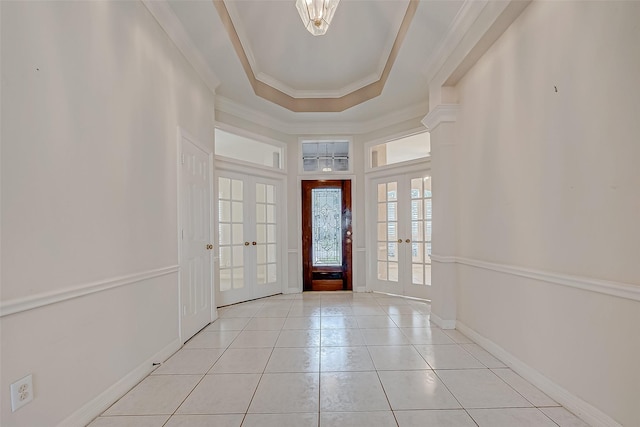 entryway featuring a tray ceiling, french doors, crown molding, light tile patterned floors, and baseboards