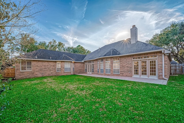 back of house with a chimney, fence, a yard, a patio area, and brick siding