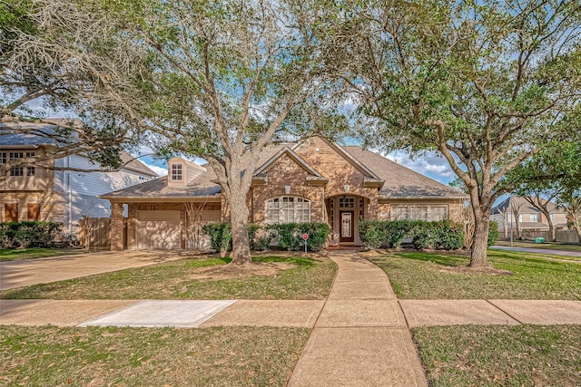 view of front of home with a front lawn, brick siding, driveway, and an attached garage