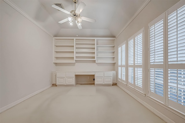 unfurnished office with vaulted ceiling, ceiling fan, built in study area, and light colored carpet