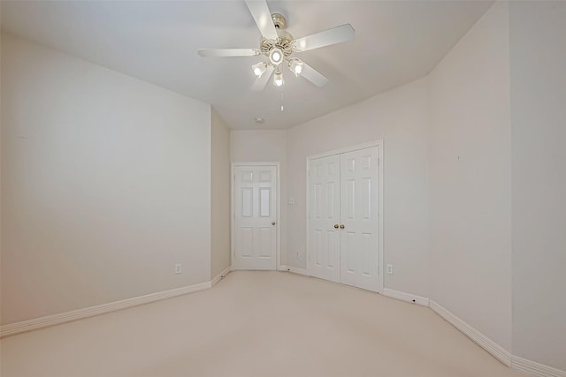 unfurnished bedroom with a closet, light colored carpet, ceiling fan, and baseboards