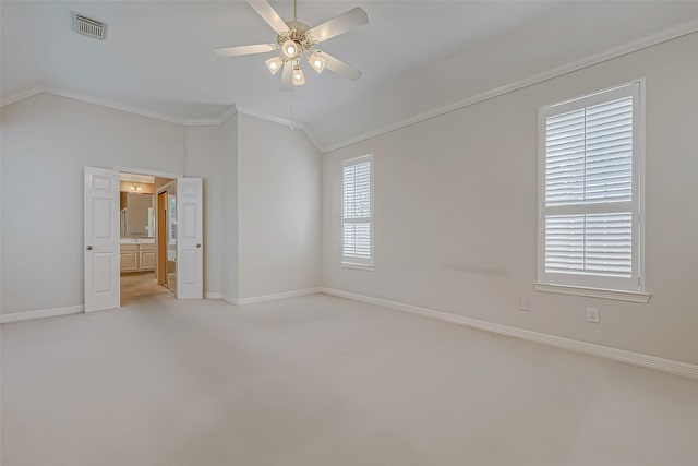 spare room featuring lofted ceiling, ceiling fan, visible vents, baseboards, and crown molding