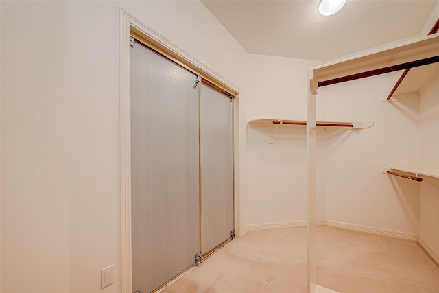 walk in closet featuring light colored carpet