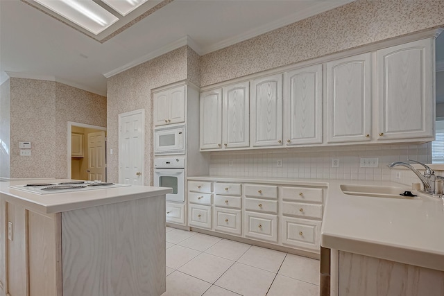 kitchen with light countertops, a sink, white appliances, a peninsula, and wallpapered walls