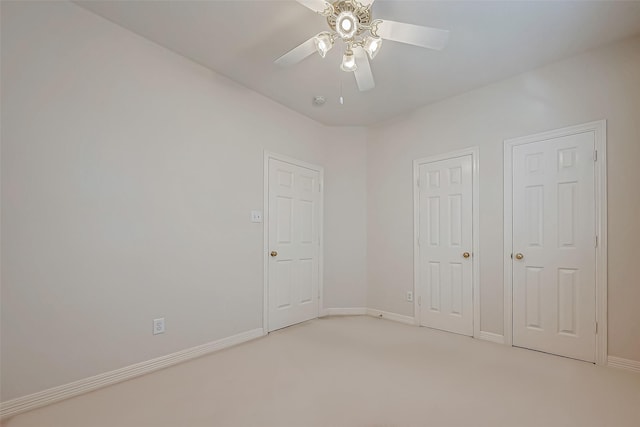 unfurnished bedroom featuring light carpet, baseboards, and a ceiling fan