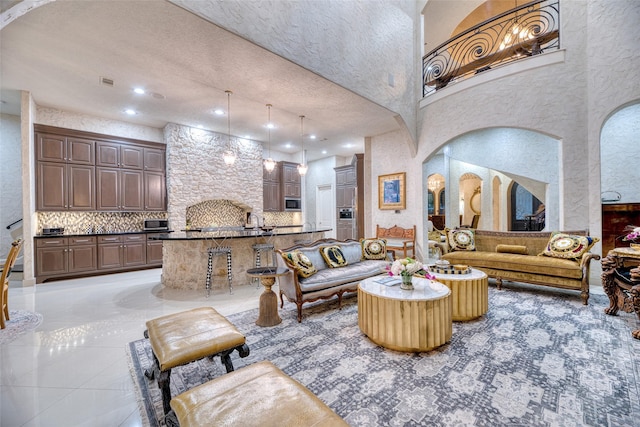 living area with light tile patterned floors, visible vents, arched walkways, a towering ceiling, and recessed lighting