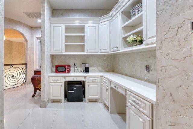 kitchen with arched walkways, open shelves, light countertops, visible vents, and white cabinets