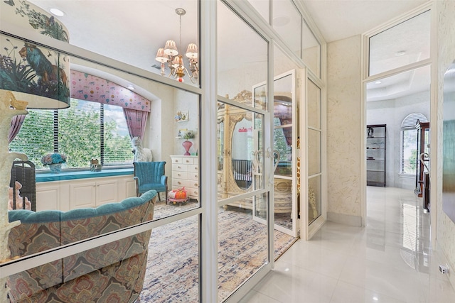 bathroom featuring baseboards, plenty of natural light, tile patterned flooring, and an inviting chandelier